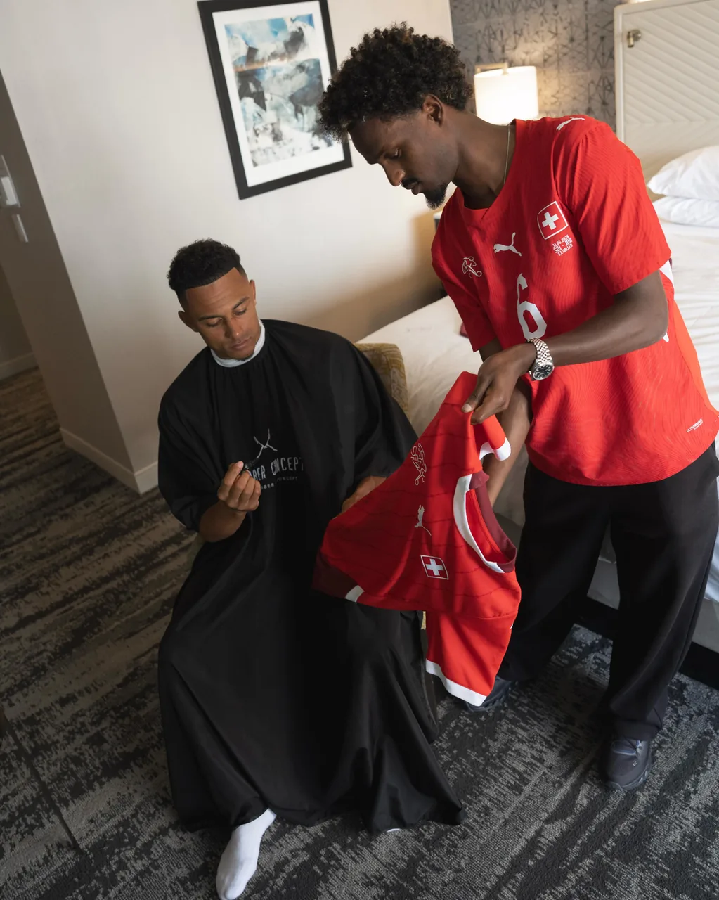 Henok réalise une coupe à un joueur de la Nati, cape Barber Concept, au Mondial 2026