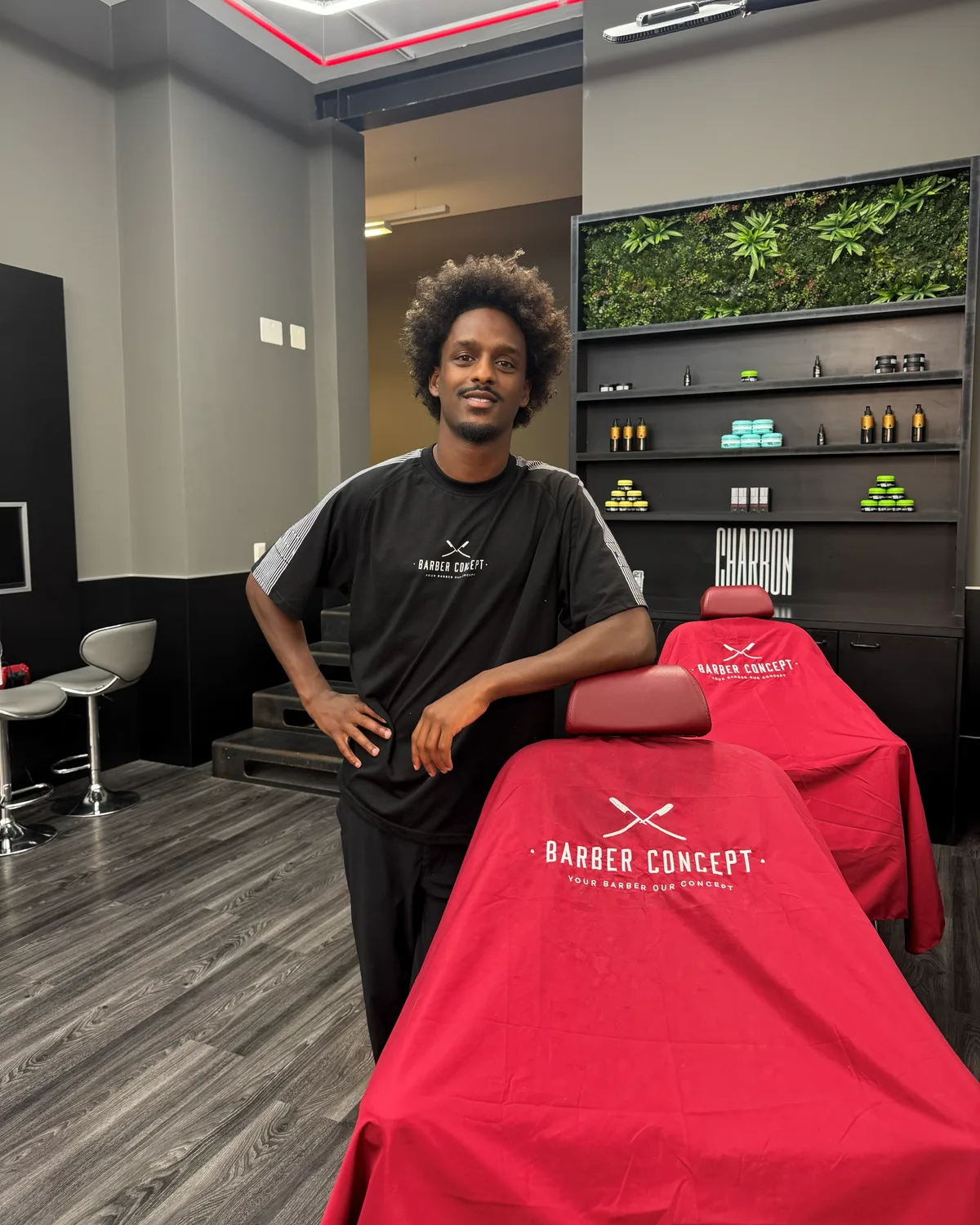Henok dans un salon Barber Concept, à côté des fauteuils préparés